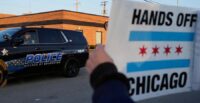 A police guards the designated protest area as protesters gather outside an ICE processing facility in the Chicago suburb of Broadview, Illinois