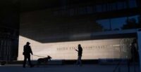 A police officer inspects the exterior of a federal courthouse with the aid of a canine