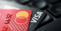 Visa and Mastercard cards are placed on a keyboard in this illustration