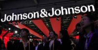 People gather next to a logo of Johnson & Johnson at the company’s booth at the 8th China International Import Expo in Shanghai, China