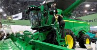 Attendees climb down from a John Deere X9 combine