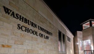 Exterior of a building at night with a sign on it reading "WASHBURN UNIVERSITY SCHOOL OF LAW"