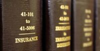 Law books on a shelf with one title in focus that reads "INSURANCE"